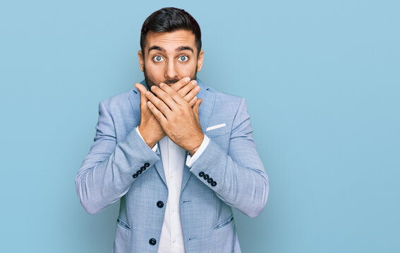 Young hispanic man wearing business jacket shocked covering mouth with hands for mistake. secret concept.
