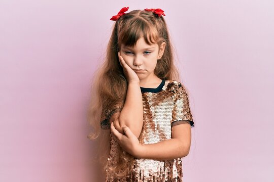 Little caucasian girl kid wearing festive sequins dress thinking looking tired and bored with depression problems with crossed arms.