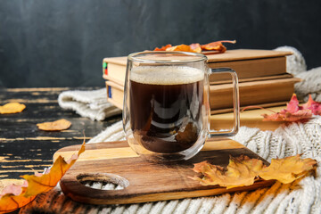 Beautiful autumn composition with cup of coffee and books on dark wooden background