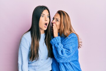 Hispanic family of mother and daughter wearing wool winter sweater hand on mouth telling secret rumor, whispering malicious talk conversation - obrazy, fototapety, plakaty