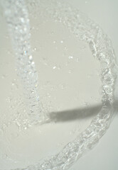 A jet of water pours on the white surface. Water bubbles are visible. Vertical snapshot