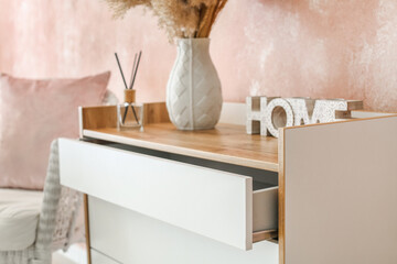 Stylish chest of drawers with decor near color wall, closeup