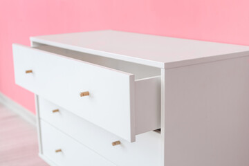Stylish chest of drawers near color wall, closeup