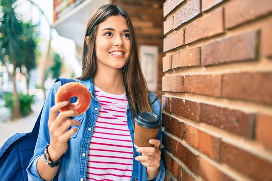 Young hispanic student girl smiling happy having breakfast at the city.