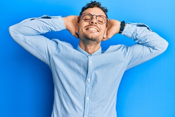 Young hispanic man wearing casual clothes and glasses relaxing and stretching, arms and hands...