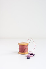 Pink sewing threads spool with sewing needle and buttons