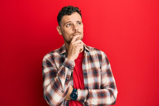 Young hispanic man wearing casual clothes thinking concentrated about doubt with finger on chin and looking up wondering