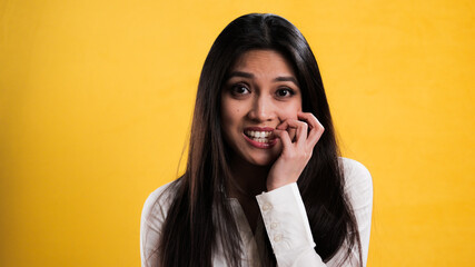 Young excited woman chews on her fingernails - studio photography