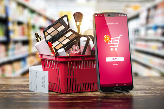 Cosmetics And Beauty Products Buying Online Concept. Shopping Basket With Makeup Products And Mobile Phone On Shelf Of Cosmaetics Shop.