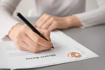 Woman signing decree of divorce at table, closeup
