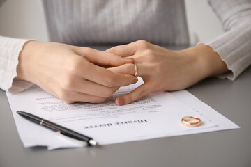 Woman taking off her wedding ring at table, closeup