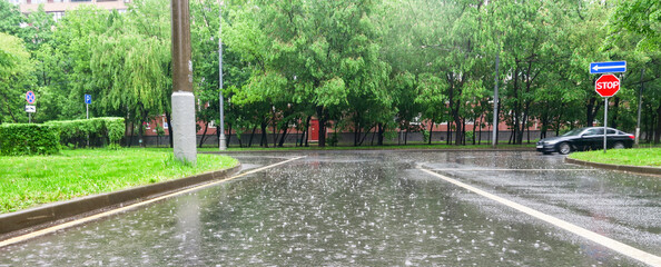 Heavy rain with hail in the city on a summer day. Large puddles on the roadway. Wet road with puddles of spray.