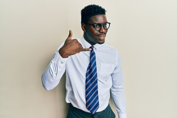 Handsome black man wearing glasses business shirt and tie smiling doing phone gesture with hand and fingers like talking on the telephone. communicating concepts.