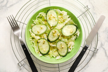 Bowl of tasty salad with fresh vegetables on light background