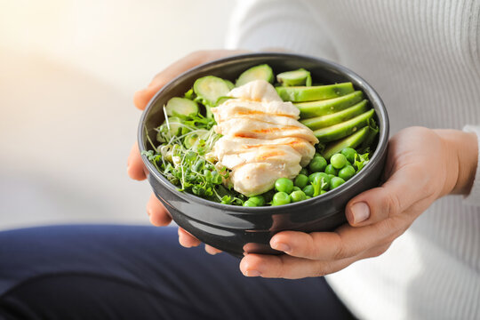 Woman holding bowl of tasty salad with fresh vegetables and chicken, closeup