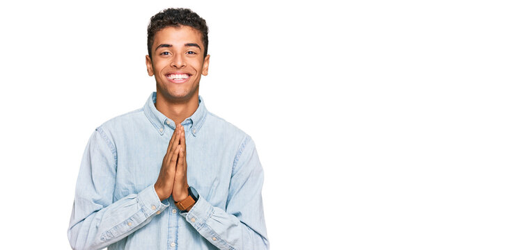 Young handsome african american man wearing casual clothes praying with hands together asking for forgiveness smiling confident.