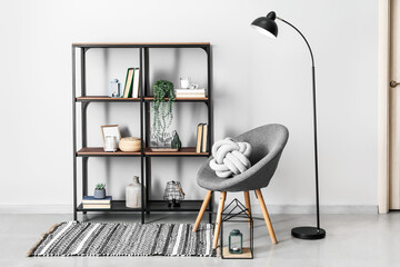 Modern book shelf with armchair and lamp near white wall in room