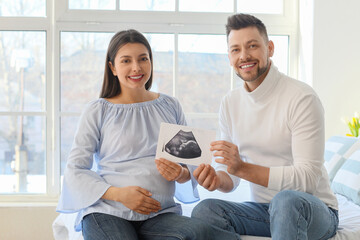 Beautiful pregnant couple with sonogram image at home