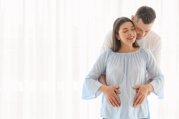Beautiful pregnant couple near window at home