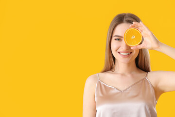 Beautiful young woman with orange on color background