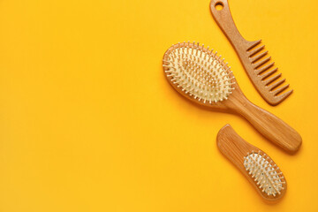 Wooden hair comb and brushes on color background