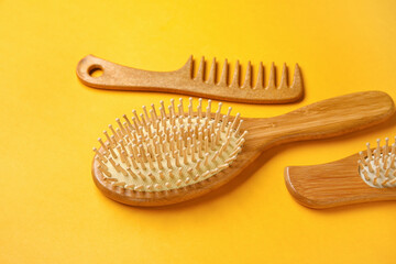 Wooden hair comb and brushes on color background