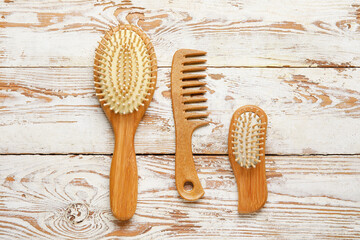 Hair comb and brushes on white wooden background