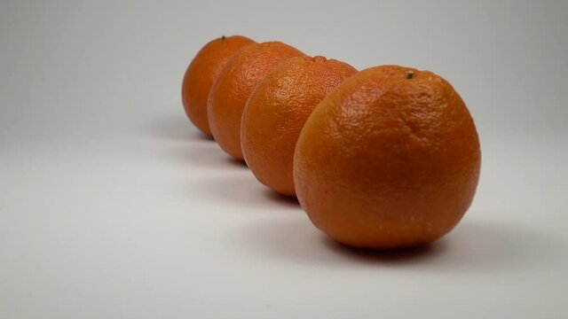 Ripe grapefruits stand in row on a white table, rotation, slow motion