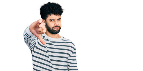 Young arab man with beard wearing casual striped sweater looking unhappy and angry showing rejection and negative with thumbs down gesture. bad expression.