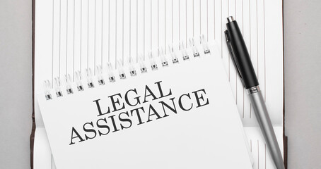 Words legal assistance text on notepad and pen
