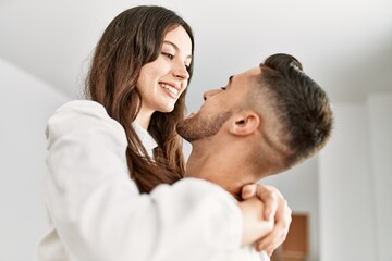 Young hispanic man holding woman in arms and hugging at new home.