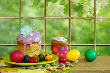 Easter still life. Easter cakes and colorful eggs on the background of a window in rain drops - 429833106