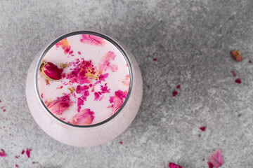 pink moon milk in glass, midnight relaxing drink, roses, grey background, top view