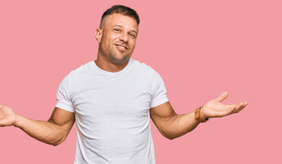 Handsome muscle man wearing casual white tshirt smiling showing both hands open palms, presenting and advertising comparison and balance
