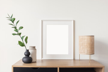 Blank picture frame mockup in home interior design. Living room, commode with lamp and vases. View of modern scandinavian style interior with artwork template on a white wall.