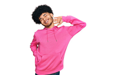 Fototapeta na wymiar Young african american man with afro hair wearing casual pink sweatshirt stretching back, tired and relaxed, sleepy and yawning for early morning