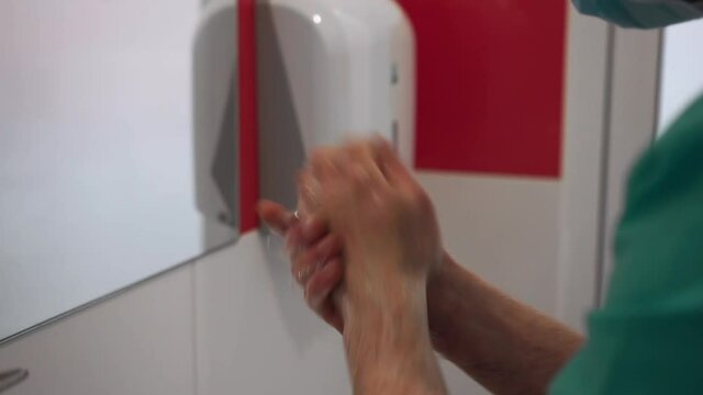 The doctor in a special form and in a mask prepares for operation and carefully washes hands between fingers and palms up to elbows with a soap solution.