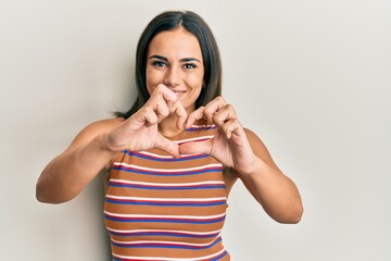 Young brunette woman wearing casual clothes smiling in love doing heart symbol shape with hands. romantic concept.