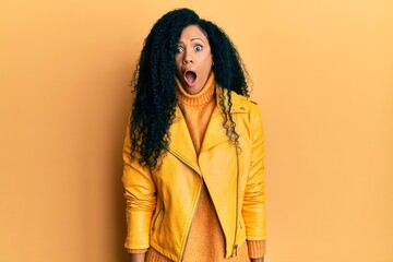 Middle age african american woman wearing wool winter sweater and leather jacket afraid and shocked with surprise and amazed expression, fear and excited face.