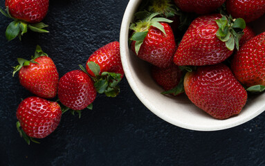 Fresh strawberries in a bowl on a dark background