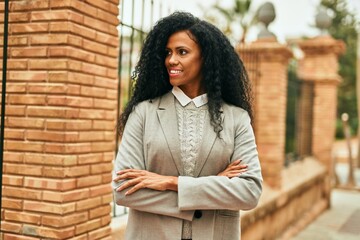 Fototapeta premium Middle age african american businesswoman smiling happy with arms crossed at the city.