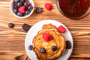 Pancakes And Berries With Honey On Wooden Background
