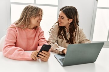 Young couple smiling happy working using laptop and smartphone at home.