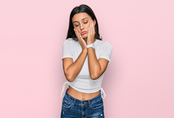 Young hispanic girl wearing casual white t shirt tired hands covering face, depression and sadness, upset and irritated for problem