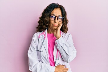 Middle age hispanic woman wearing doctor uniform and glasses thinking looking tired and bored with depression problems with crossed arms.