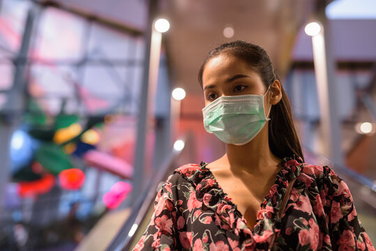 Portrait of woman wearing face mask for protection against coronavirus Covid-19 at escalator outdoors