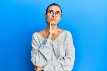 Young hispanic woman wearing casual clothes thinking concentrated about doubt with finger on chin and looking up wondering
