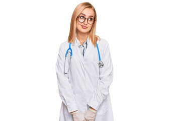 Fototapeta premium Beautiful caucasian woman wearing doctor uniform and stethoscope smiling looking to the side and staring away thinking.