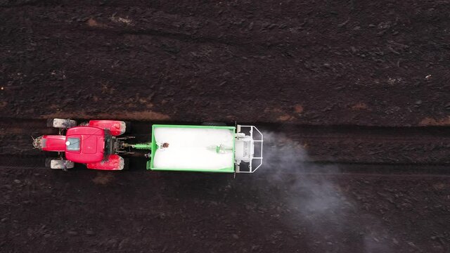 Aerial view of Tractor spreads dry fertilizers. Seasonal increase in germination and crop yield.