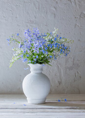 spring flowers in vase on background white old wall